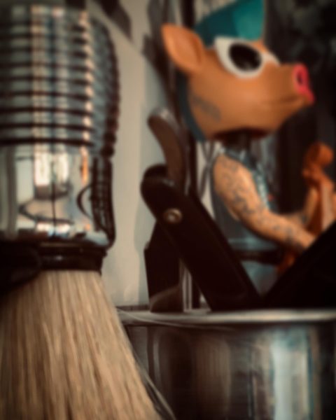 A shave brush left, a razor in the middle and a decorative pig head in the right